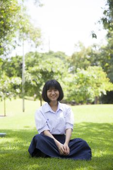 Girls relaxing on the lawn. Within the park with trees and greenery.