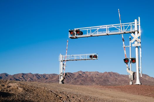 A busy railroad crossing in front of desert mountains