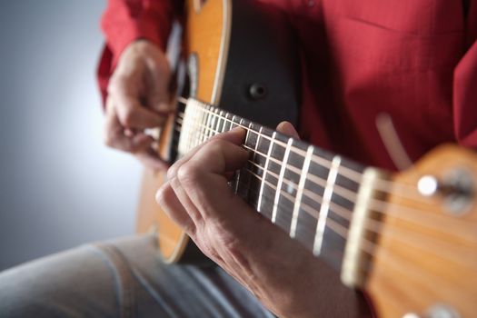 closeup of hands of a musician playing acoustic guitar