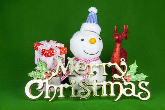 Christmas gift, baubles, snowman and other christmas ornaments on green background.