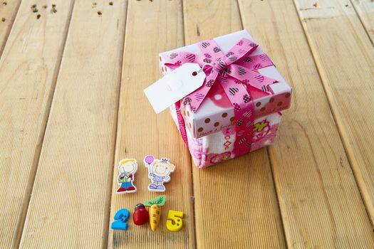 Pink Christmas gift box full of xmas  on wood background.
