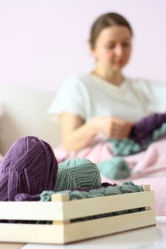 happy young woman knitting on sofa
