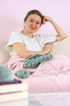 happy young woman knitting on sofa