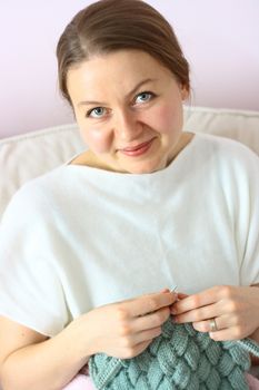 happy young woman knitting on sofa