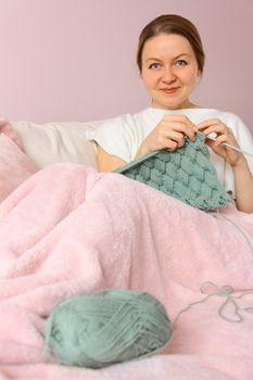 happy young woman knitting on sofa