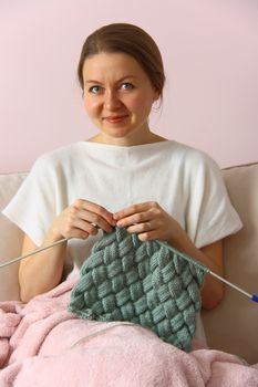 happy young woman knitting on sofa