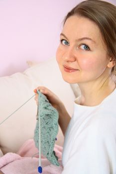 happy young woman knitting on sofa