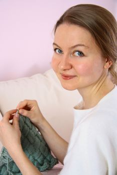 happy young woman knitting on sofa