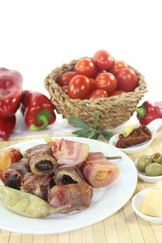 Tapas stuffed with prunes, figs, apricots and bacon on a light background