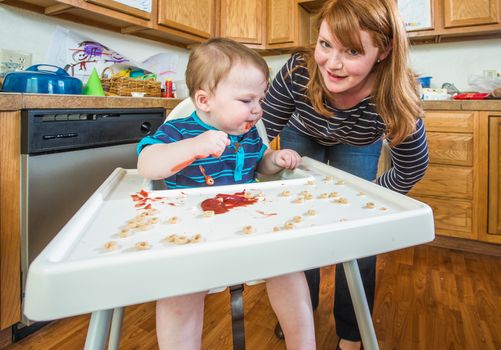 Mother in kitchen smiles as baby eats