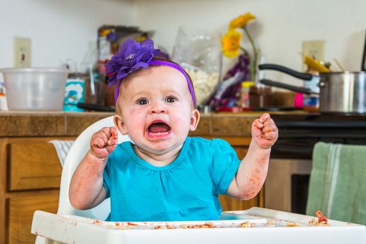 A baby girl throws a tantrum in the kitchen