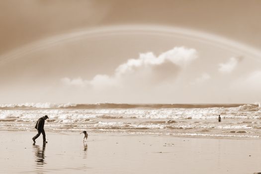 one man and his dog on Ballybunion beach county Kerry Ireland with a rainbow in sepia