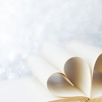 Heart shaped book pages on glitter background