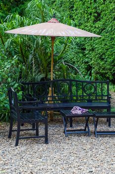 Wooden Bench and table in a pebble garden with umbrella