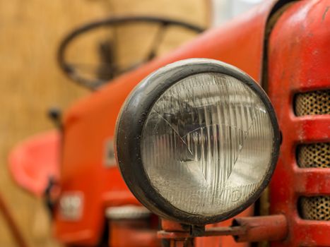 Closeup of a headlight on an old red rusty tractor