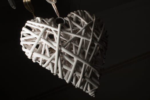 A low key close up of a white wicker heart.