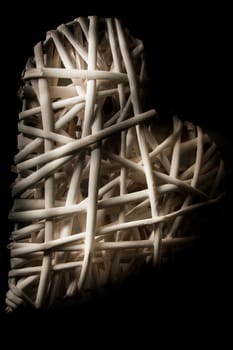 A low key close up of a white wicker heart.