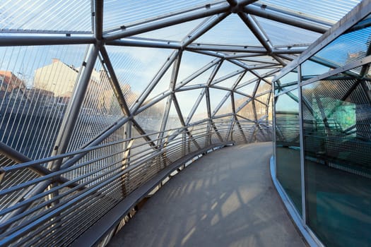 Graz, Austria - January 16, 2011: Island on Mur river connected by a modern steel and glass bridge, Styria, Graz, Austria