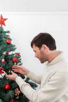 30-35, adult, artificial, background, balls, brown, caucasian, celebration, christmas, decorating, decorations, eyes, festive, garland, green, handsome, happy, holiday, male, man, men, model, old, ornaments, person, pine, pleasure, property, red, releases, santa, seasonal, smiling, sweater, tall, tradition, tree, vertical, white, winter, xmas, years, young