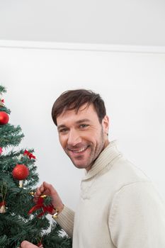 30-35, adult, artificial, background, balls, brown, caucasian, celebration, christmas, decorating, decorations, eyes, festive, garland, green, handsome, happy, holiday, male, man, men, model, old, ornaments, person, pine, pleasure, portrait, property, red, releases, santa, seasonal, smiling, sweater, tall, tradition, tree, vertical, white, winter, xmas, years, young, look, looking, camera, smile