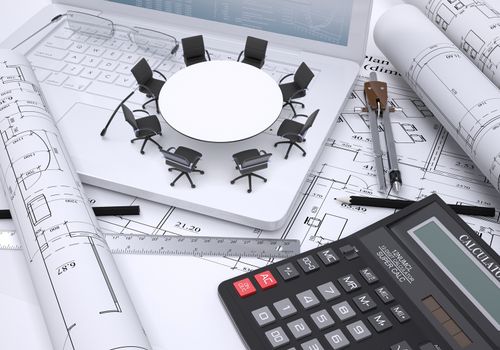Miniature round table with chairs placed on laptop, calculator and a few other tools all on spread architectural drawings, couple of scrolled drawings beside. Concept of construction business.