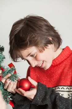 10-12, anticipation, backround, ball, boy, brown, casual, caucasian, christmas, christmastime, decorating, decorations, green, hair, hold, holding, holiday, home, indoors, look, male, model, old, people, profile, property, red, releases, situation, smile, sweater, teenager, the, tree, vertical, white, winter, xmas, years