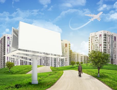 Businessman walking along road running through green hills with a few trees. Blank billboard with lighting on foreground. High-rise buildings with jet lowering above as backdrop