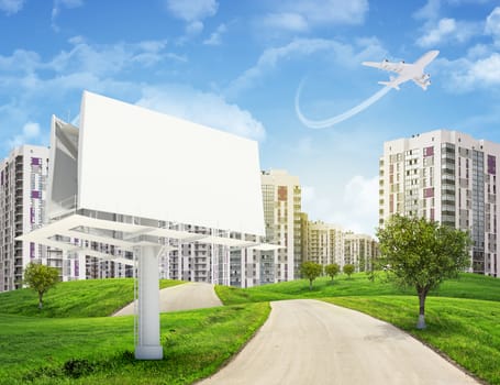 Road running through green hills with some trees, towards high-rise buildings with jet lowering above. Blank billboard with lighting on foreground.