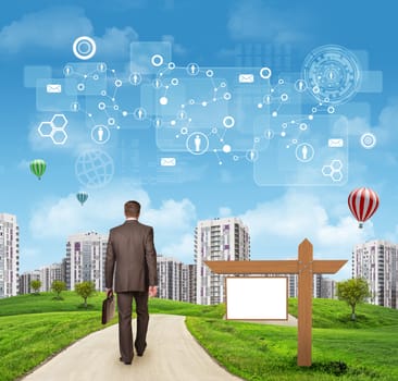 Businessman walking along road running through green hills with a few trees, passing by blank signboard. High-rise buildings with a few air-baloons above as backdrop. Schemes, rectangles and other virtual items in sky