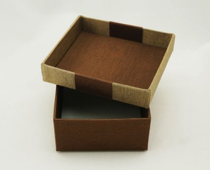 Opened gift box packaging, the exterior is made from fabric with gold and brown color.                               
