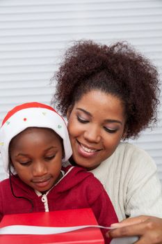 30-35, 4-6, african, apartment, attractive, beautiful, black, box, bun, child, christmas, couple, curly, daughter, decorating, family, female, gift, girl, girls, happy, hat, holding, home, homey, house, household, life, living, love, model, mother, offering, old, parent, person, pretty, property, releases, ribbon, room, sitting, two, vertical, woman, years, young