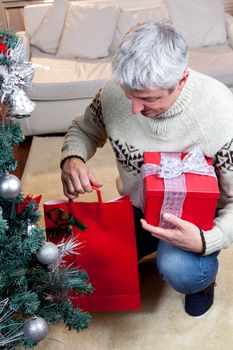 35-40, artificial, bags, balls, boxes, candy, caucasian, christianity, christmas, costume, decorations, garland, gifts, giving, holiday, kneeling, male, man, model, old, ornaments, packages, person, pine, presents, property, putting, red, releases, religion, ribbon, santa, shiny, stocking, tissue, tree, underneath, vertical, wrapped, xmas, years, green, silver, carpet