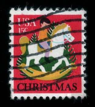 Child rides a white rocking horse. Christmas postage stamp, uloaded in 2014