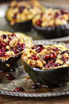 Acorn squash stuffed and baked with brown sugar, walnuts and cranberries, ready for holiday dinners. Extreme shallow depth of field with beautiful bokeh.