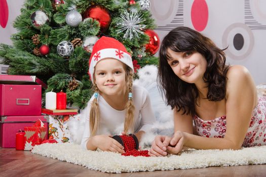 Mum and daughter lie on the five-year rug Christmas tree