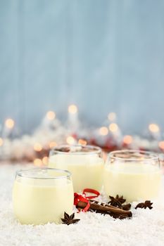 Three glasses of fresh eggnog with cinnamon sticks and star of anise ready for the Christmas season with copy space. Extreme shallow depth of field.