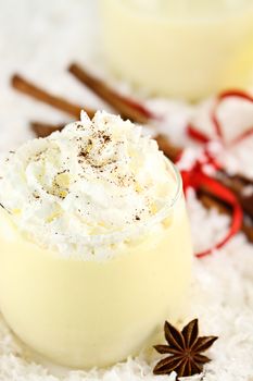 Fresh eggnog with whipped cram and sprinkled with cinnamon. Extreme shallow depth of field with selective focus on whipped cream.