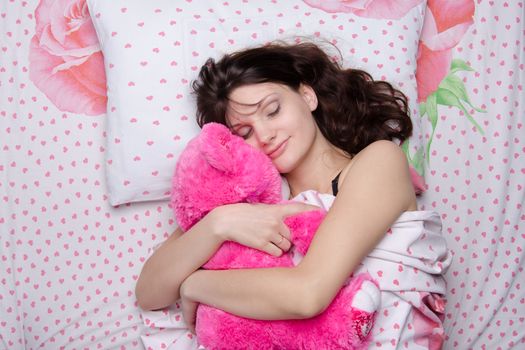 Young beautiful woman sleeping in bed with teddy bear