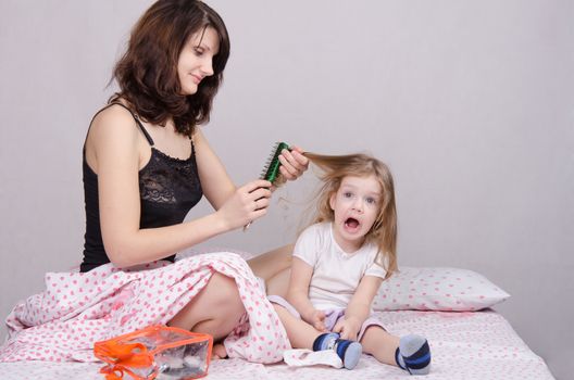 Mom and daughter with an excellent mood sitting on the bed