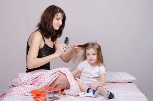 Mom and daughter with an excellent mood sitting on the bed