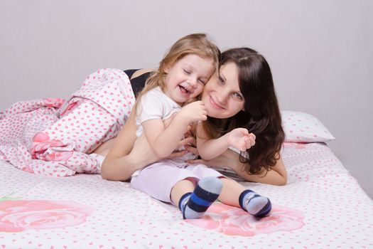 Mom and daughter with an excellent mood sitting on the bed