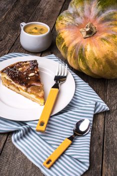 Pumpkin pie with cream soup on wooden table in Rustic style