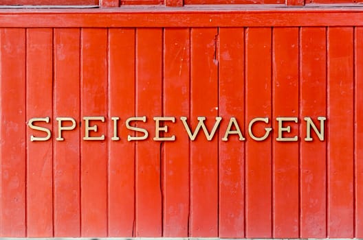 The word "Dining Car" is written on the side of a very old retro stainless steel and red train car.