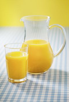 A glass and pitcher with orange juice. Short depth-of-field.