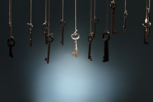 Old keys hanging on strings. One key in the middle is in spotlight focus.