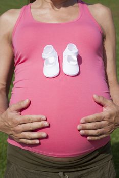 pink pregnant woman with baby bootees in hand