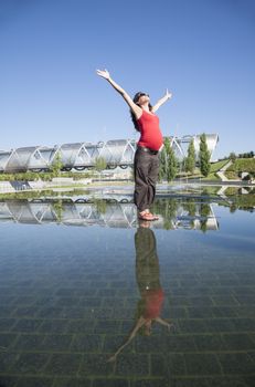 happy pregnant woman open arms on water surface in Madrid city