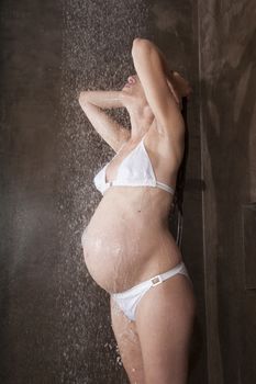 pregnant woman with white bikini under shower water