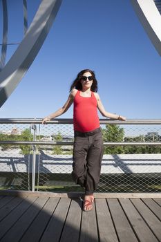 front pregnant woman leaning on railing blue sky background