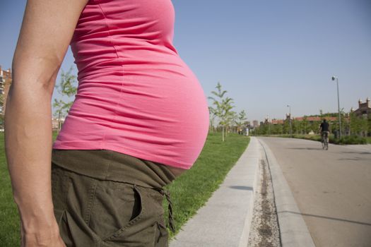 tummy pregnant woman with pink shirt at park